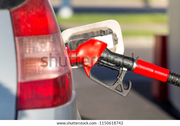 car is at\
gas station. gun is inserted into fuel tank at fuel station.\
Refueling. Pours gasoline into the tank of\
car.