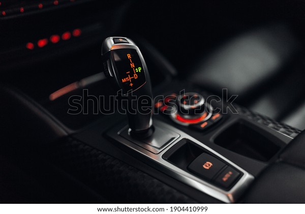 Car gearbox shift handles stick\
in parking position. The dark interior of the car with\
backlihgt