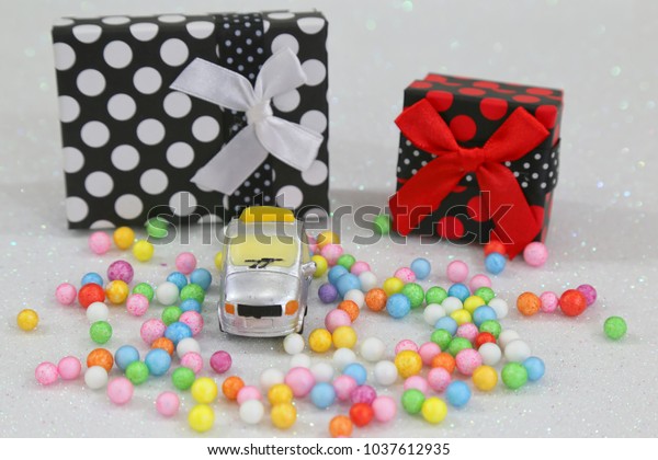  Car with gift package and colorful bubbles on the white\
background  
