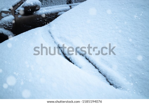 Car glass and cleaning brushes covered with snow\
frozen. Snow falls.