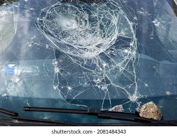 Car Glass Shattered By A Stone. Broken Car Windshield. Criminal Incidents. Vandals, Hooligans Mutilated The Car, Smashed The Windshield