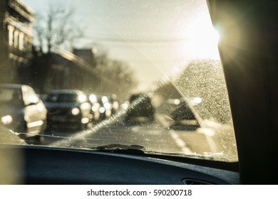 Car Glass With Unclean Texture. Blurred Road On Background. Morning Sunlight.