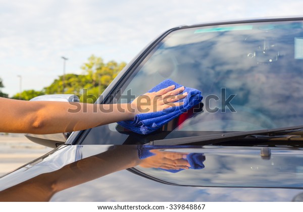 Car glass, windscreen clean, maintenance, service\
or detailing. Wipe polish by asian women hand, manual worker, blue\
microfiber towel and cleaner. To remove dust and dirt. Result\
gloss, shine, shiny.