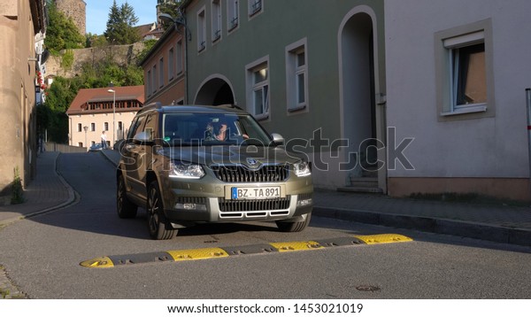 A car goes over a speed bump in a residential\
street. Photo taken in Bautzen, Saxony / Germany on June 20, 2019. \
                             