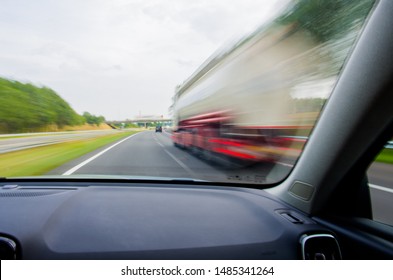 Car Is Going To Overtake White / Red Truck On Dutch/European Two-lane Highway At High Speed. Dashboard View With Motion Blur.