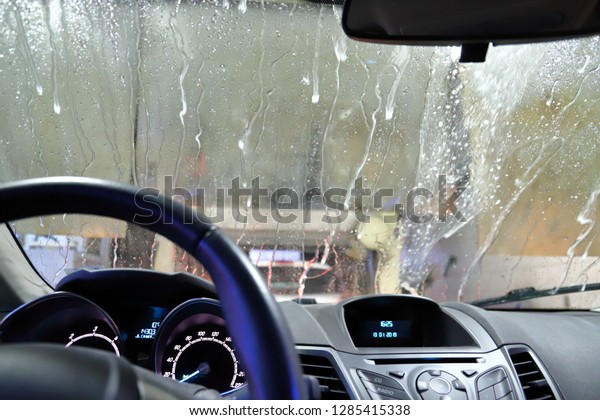 A car going through an automated car wash seen from\
inside the cabin