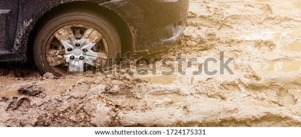 The car got\
stuck on a dirt road in the mud. Wheel of a car stuck in the mud on\
the road. Car on a dirt\
road.