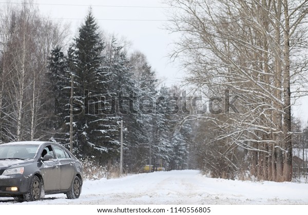 The car is gray on the road in forest. A trip to\
the countryside on a winter weekend. The car on the road in front\
of the winter park.\
