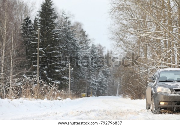 The car is gray on the road in forest. A trip to\
the countryside on a winter weekend. The car on the road in front\
of the winter park.\