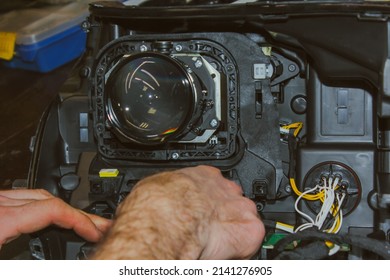 The car headlight is disassembled. Car headlight repair close-up. An auto mechanic repairs the headlight of the car. The master connects the wires in the headlight. The concept of a car service.