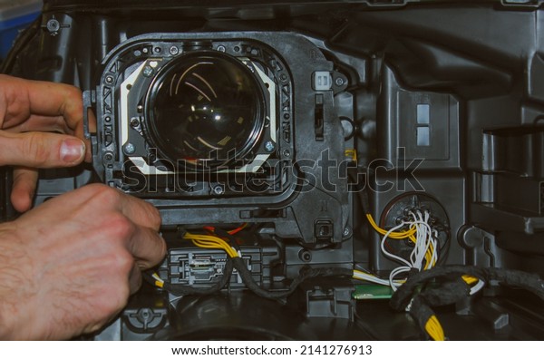 The car headlight is disassembled. Car headlight\
repair close-up. An auto mechanic repairs the headlight of the car.\
The master connects the wires in the headlight. The concept of a\
car service.