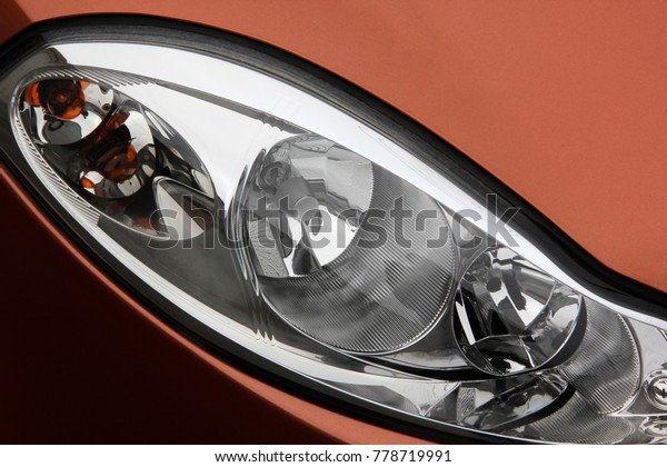Car headlight car. The car is an orange color.\
Lighting devices of\
transport.
