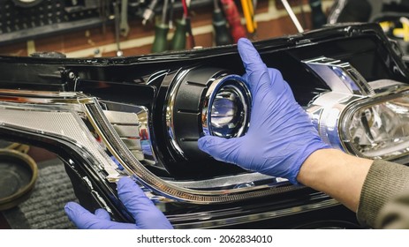 Car headlight in repair close-up. An auto mechanic wearing gloves installs the lens into the headlight housing. The concept of a car service.Installation of LED lenses in the headlight. LED lenses.