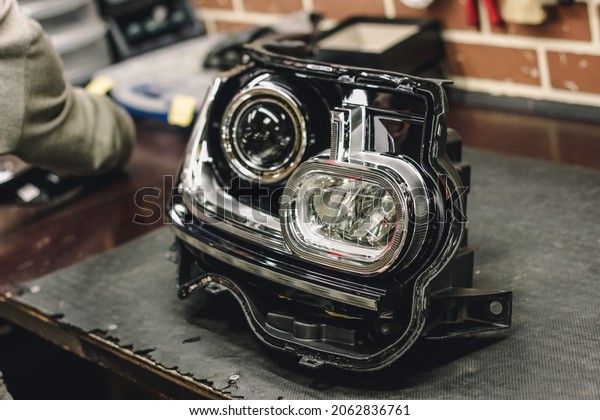 Car headlight\
in repair close-up. The concept of a car service.Installation of\
LED lenses in the headlight. LED lenses.  Automotive optics.\
Restoration of optics.