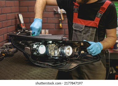 Car Headlight In Repair Close-up. The Car Mechanic Installs The Lens In The Headlight Housing. The Concept Of A Car Service.Installation Of LED Lenses In The Headlight. LED Lens.Restoration Of Optics.