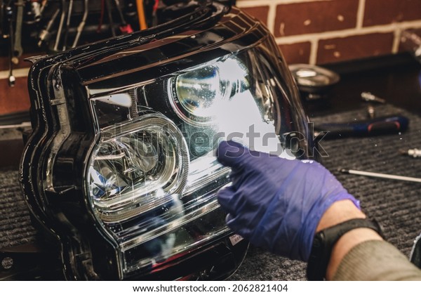 Car headlight in repair on the desktop close-up.An\
auto mechanic repairs the headlight of the car. The concept of\
repair in a car service.Dismantled headlight close-up.Car\
restoration.Headlight\
lenses
