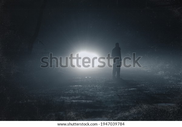 Car headlights\
back lighting a man and trees on a spooky foggy night in a forest.\
With a grunge, weathered\
edit