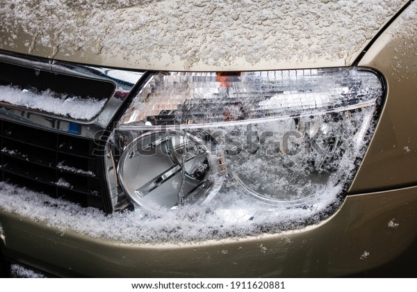 Car headlights\
covered with snow close up.