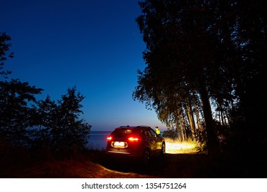 Car With Headlights On The Background Of The Forest And Night Sky. Camping