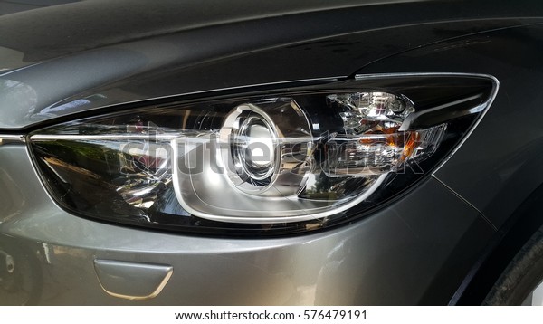 car headlights, selective focus point on headlight\
lamp car, car front light, metallic headlight of white car,\
automotive part
