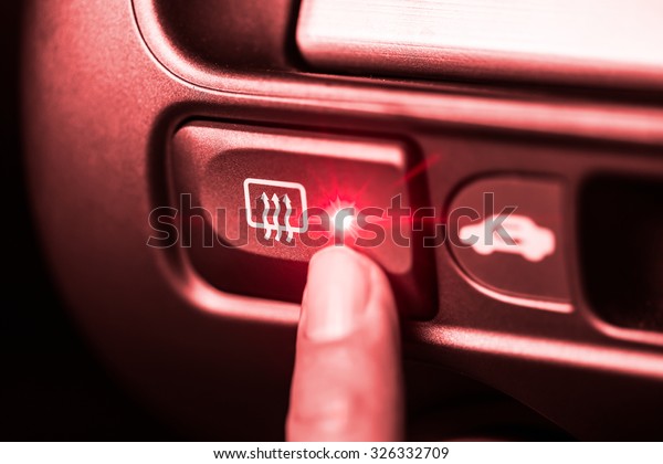 Car heater button with finger press red color\
tone effect.