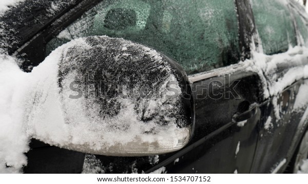 Car heating melts snow and ice from the
car. Car's side view mirror of a modern
car.