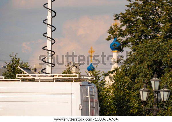 A car with a hidden camera on the roof. A white\
car is watching through the cameras for the citizens of the city.\
Against the background of the Orthodox, Christian church with\
golden crosses. Closeup.