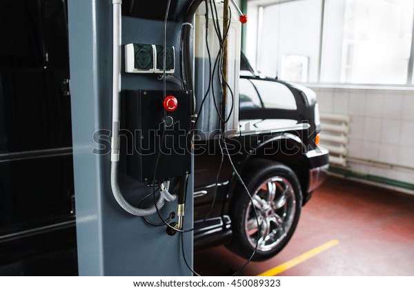 Car hoist remote control in garage closeup. Car\
on service maintenance in garage before lifting, focus on hoist\
remote control with red\
button.