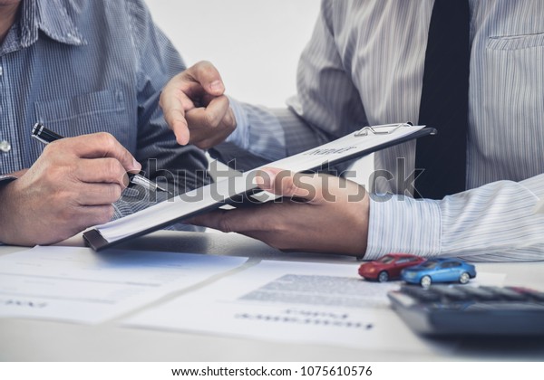 Car and Home insurance concept, broker agent\
presenting and consult to customer to decision making sign\
insurance form agreement, home and car\
model.