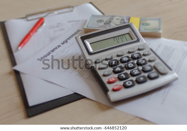 Car and Homeowner Insurance form with\
much dollars, pen and calculator. Insurance\
concept