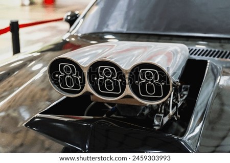 A car with a hood open and three exhaust pipes. The pipes are silver and have the number 8 on them