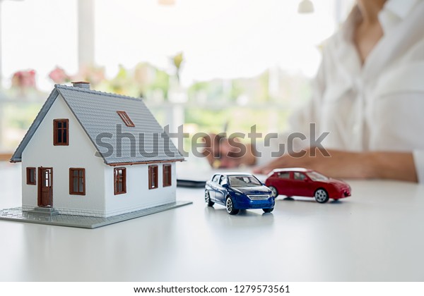 Car and House model with agent and customer
discussing for contract to buy, get insurance or loan real estate
or property background.