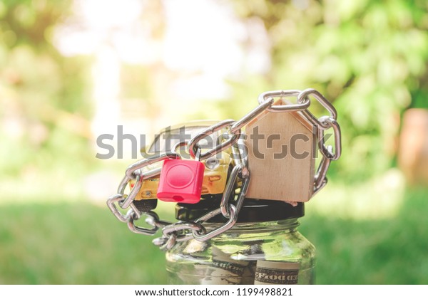 Car, house models and money in jar glass\
locked with chain and padlock. Responsibility for tax and liability\
- Businessman corporate slavery\
concept.