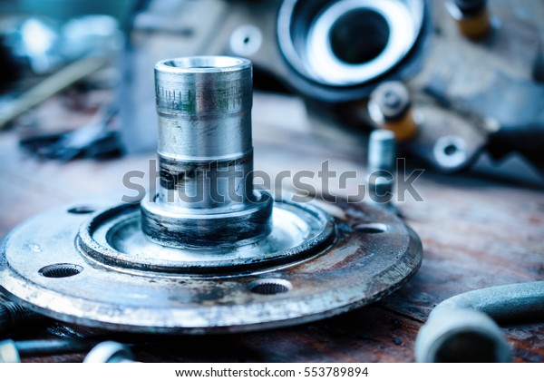 Car hub axis. Abstract industrial\
background. Old, oiled wheel hub lies on a wooden\
table.
