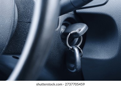 Car ignition with key inserted in steering column. Vehicle interior detail closeup. Starting engine concept. Automotive security and transportation theme. Driver perspective inside cabin.