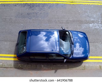 Car illegally parked on a road marked with double yellow lines, high angle view.