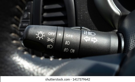 Car Indicator Stalk Showing Car Light Options Including Side Lights, Main Beam, Full Beam And Fog Lights.  Also Acts As An Indicator Stalk With Stitched Steering Wheel Blurred In The Foreground.