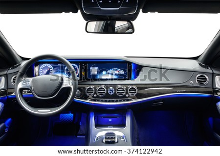 Car inside driver place. Interior of prestige modern car. Steering wheel, dashboard, display & climate control. Black cockpit with wood & metal decoration & ambient light on isolated white background.