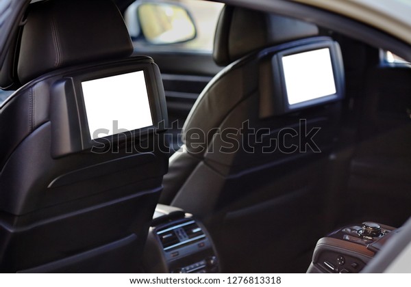 Car inside headrest\
screen mock up. Interior of prestige luxury modern car. Two white\
displays for back seats passenger with media control panel copy\
space and place for text.