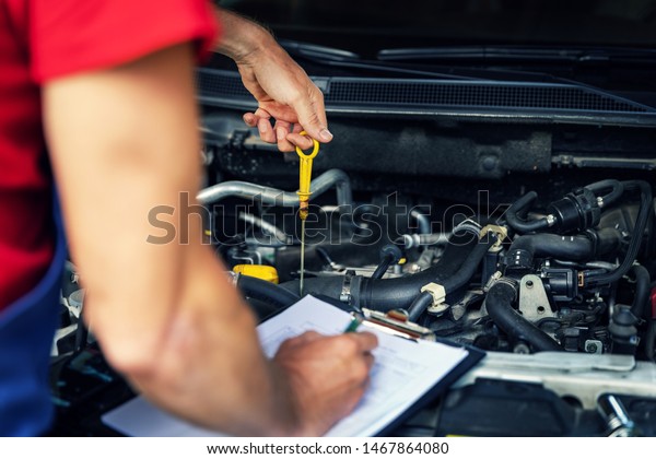 car inspection and maintenance -
mechanic check engine oil level and writing in
checklist