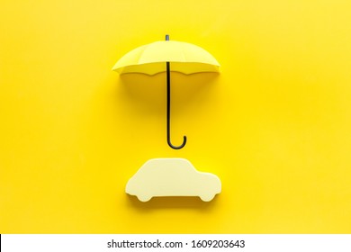 Car Insurance. Automobile Toy Under Umbrella On Yellow Background Top-down Copy Space