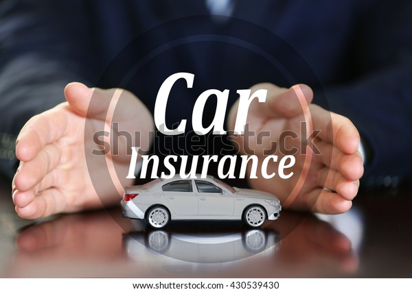 Car insurance concept. Man and model of car on\
wooden table, closeup