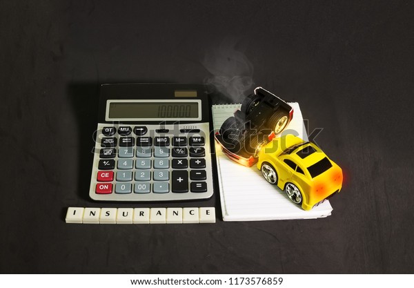 Car insurance concept, toy cars representing a\
car accident beside a\
calculator