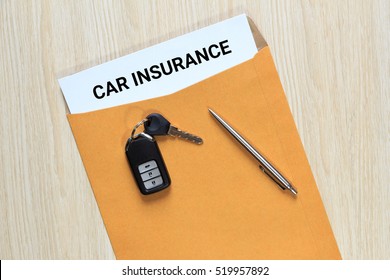 Car insurance in envelope with pen and car key remote control on table - business concept.