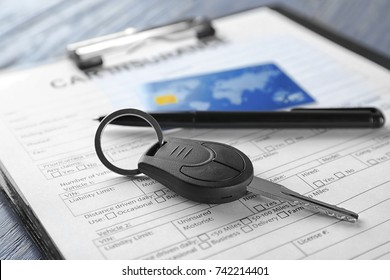 Car insurance form, credit card and key on table