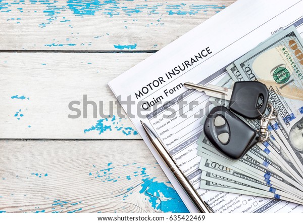 Car insurance form with car keys, pen and\
money on the old wooden\
background.