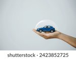 Car insurance, vehicle protection concept. Hand-protect blue toy car under a glass dome in concept car care, insurance, and repair coverage covered automobile for financial security.