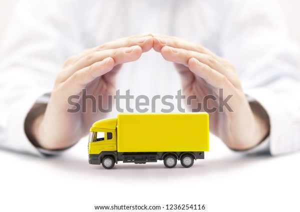 Car\
insurance. Yellow truck miniature covered by hands.\
