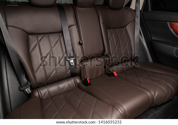 Сlose-up of the car   interior: brown natural\
leather rear seats and seat belts .\
