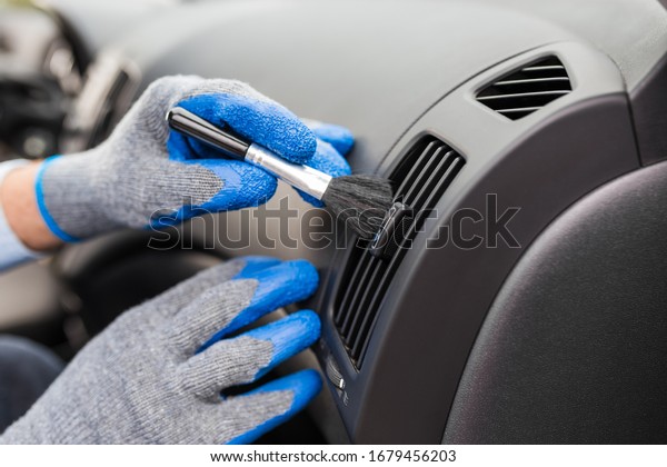 Car interior cleaning detailing. Hands wearing\
gloves holding brush.